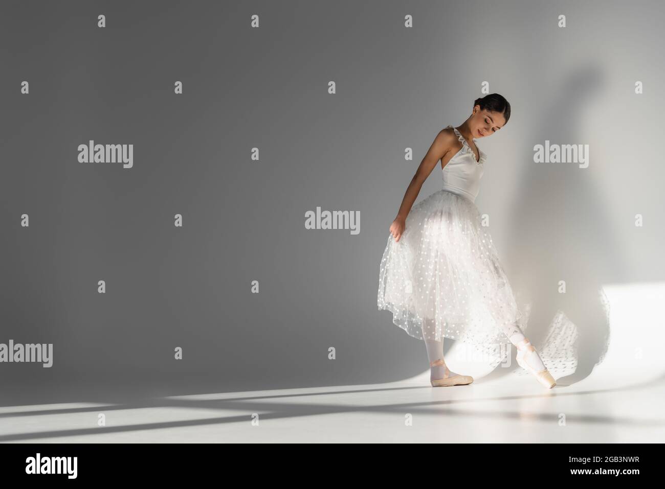 Ballerina guardando la scarpa punta su sfondo grigio Foto Stock