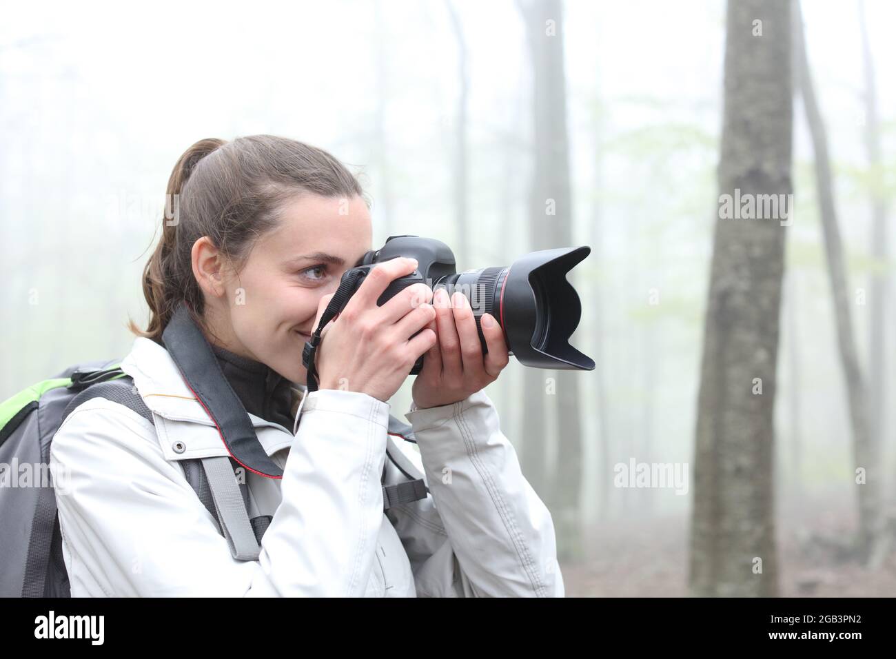 Trekker scattare foto con la fotocamera dslr in una foresta una giornata di nebbia Foto Stock