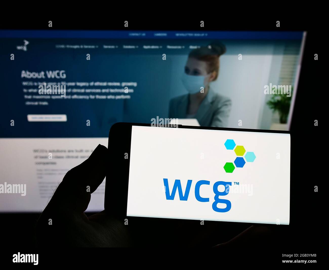 Persona che detiene smartphone con il logo della società WIRB-Copernicus Group Inc. (WCG Clinical) sullo schermo davanti al sito web. Mettere a fuoco il display del telefono. Foto Stock