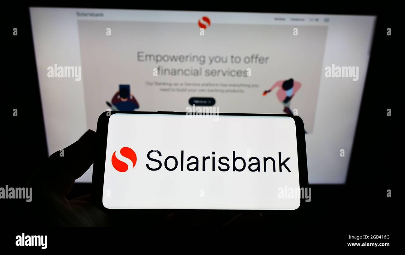 Persona che detiene smartphone con logo della società tedesca di servizi finanziari Solarisbank AG sullo schermo di fronte al sito web. Mettere a fuoco il display del telefono. Foto Stock