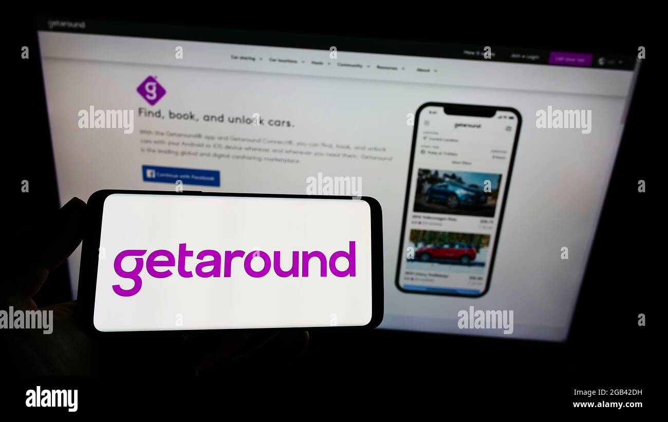 Persona in possesso di smartphone con logo della società di car sharing statunitense Getaround Inc. Sullo schermo davanti al sito Web. Mettere a fuoco il display del telefono. Foto Stock
