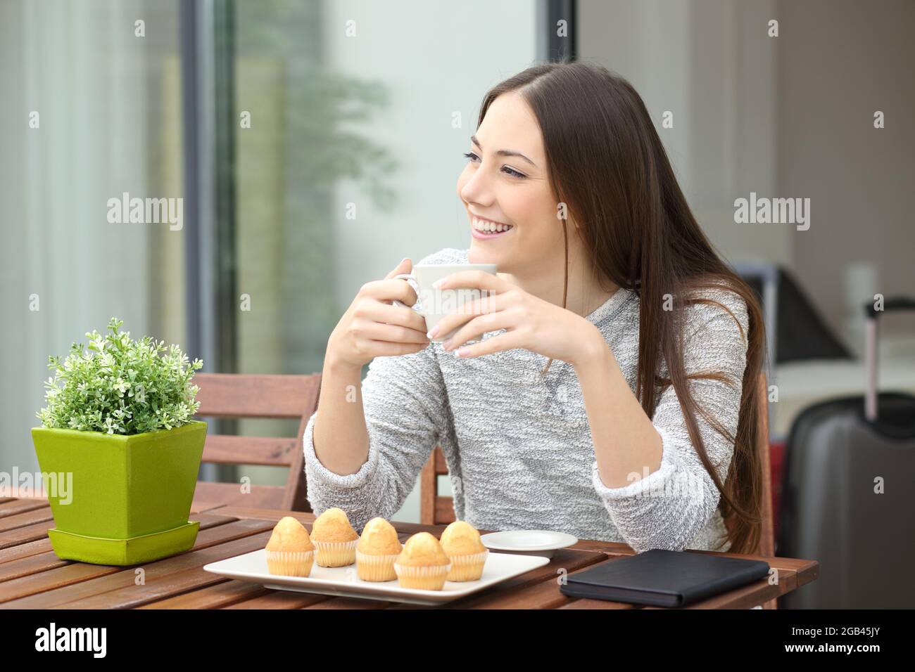 Donna che ha fatto colazione con caffè e muffin seduti sul balcone della camera d'albergo Foto Stock