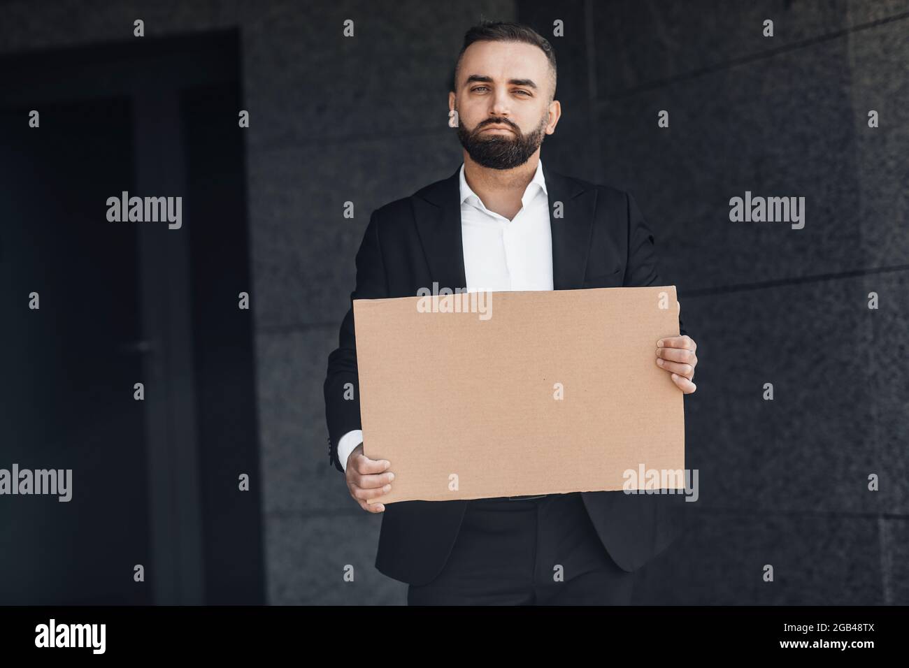 Uomo d'affari maturo protestando contro il blocco sulla strada, mostrando un cartello di cartone vuoto, mockup per il tuo testo Foto Stock