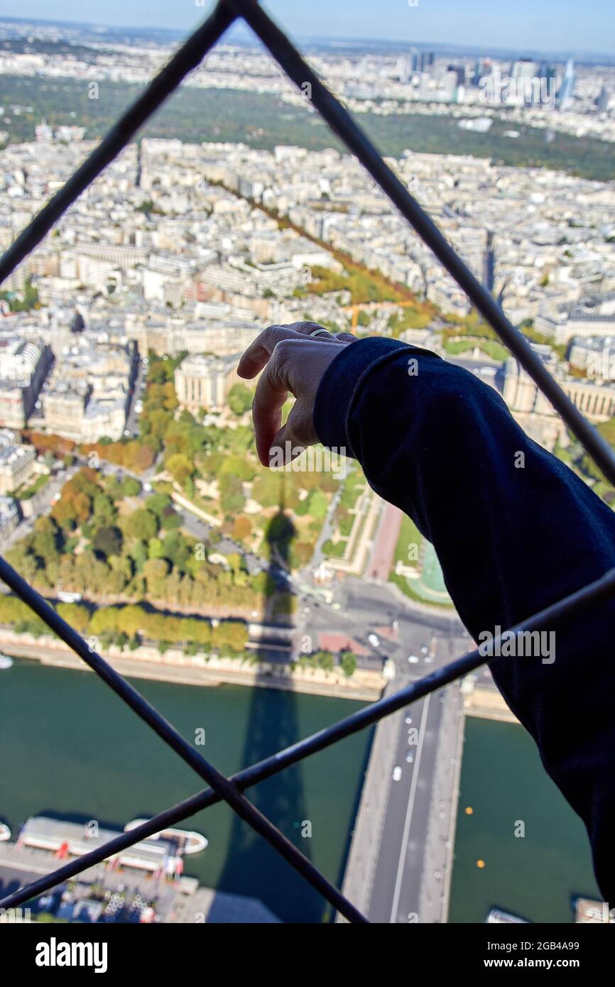La mano del turista cerca di afferrare la punta dell'ombra della Torre Eiffel a Parigi Foto Stock