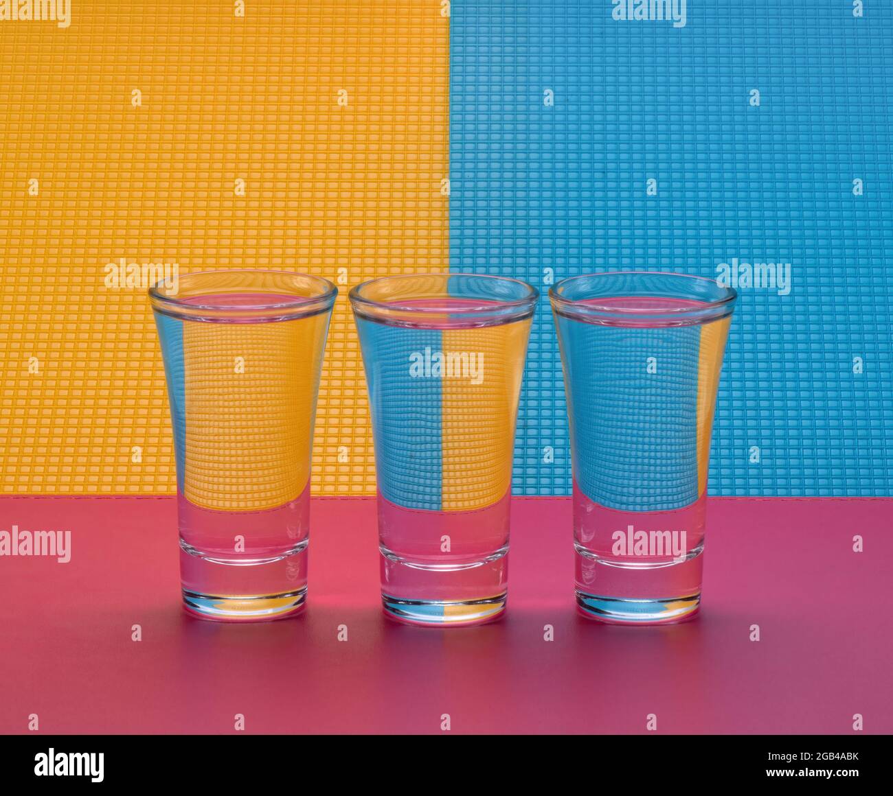 Tre bicchieri d'acqua su sfondo colorato. Ancora vita con rifrazione. Foto Stock