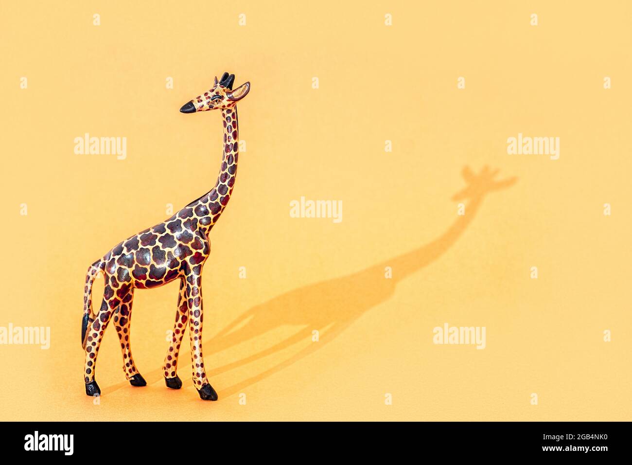 Giraffa in legno Figurine con ombra su sfondo arancione con spazio per la copia Foto Stock