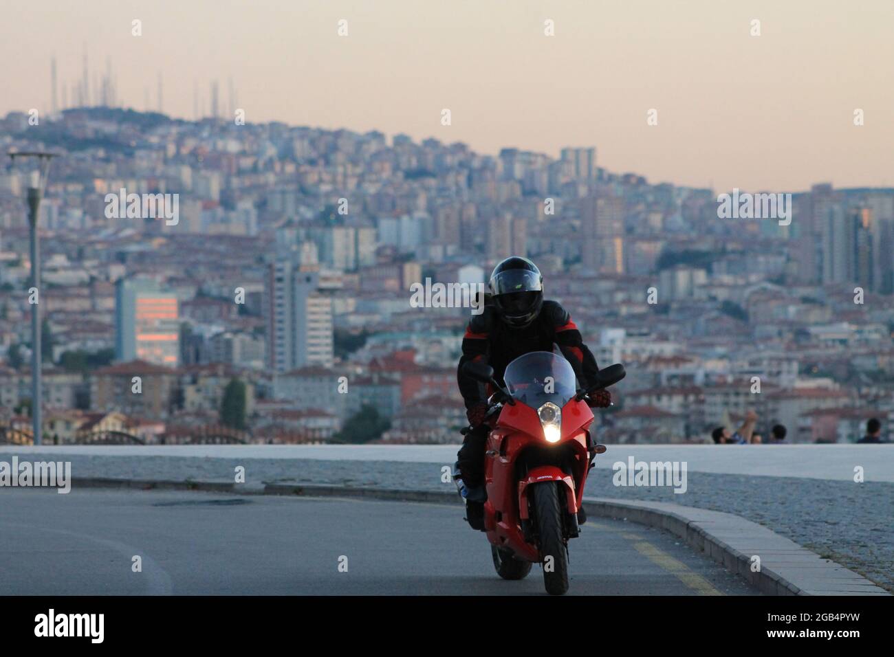 Moto uomo in tuta nera e casco in bici rossa con vista sulla città Foto  stock - Alamy