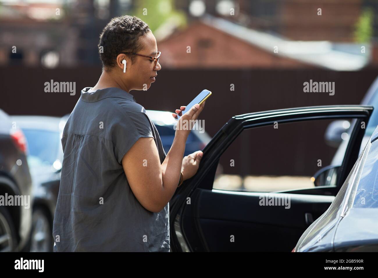 Giovane donna africana che legge un messaggio sul telefono cellulare mentre si è in auto Foto Stock