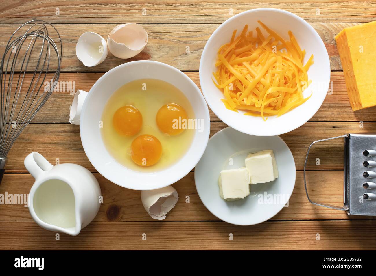 Ingredienti per la preparazione di omelette di formaggio su tavola di legno. Fotografia alimentare Foto Stock