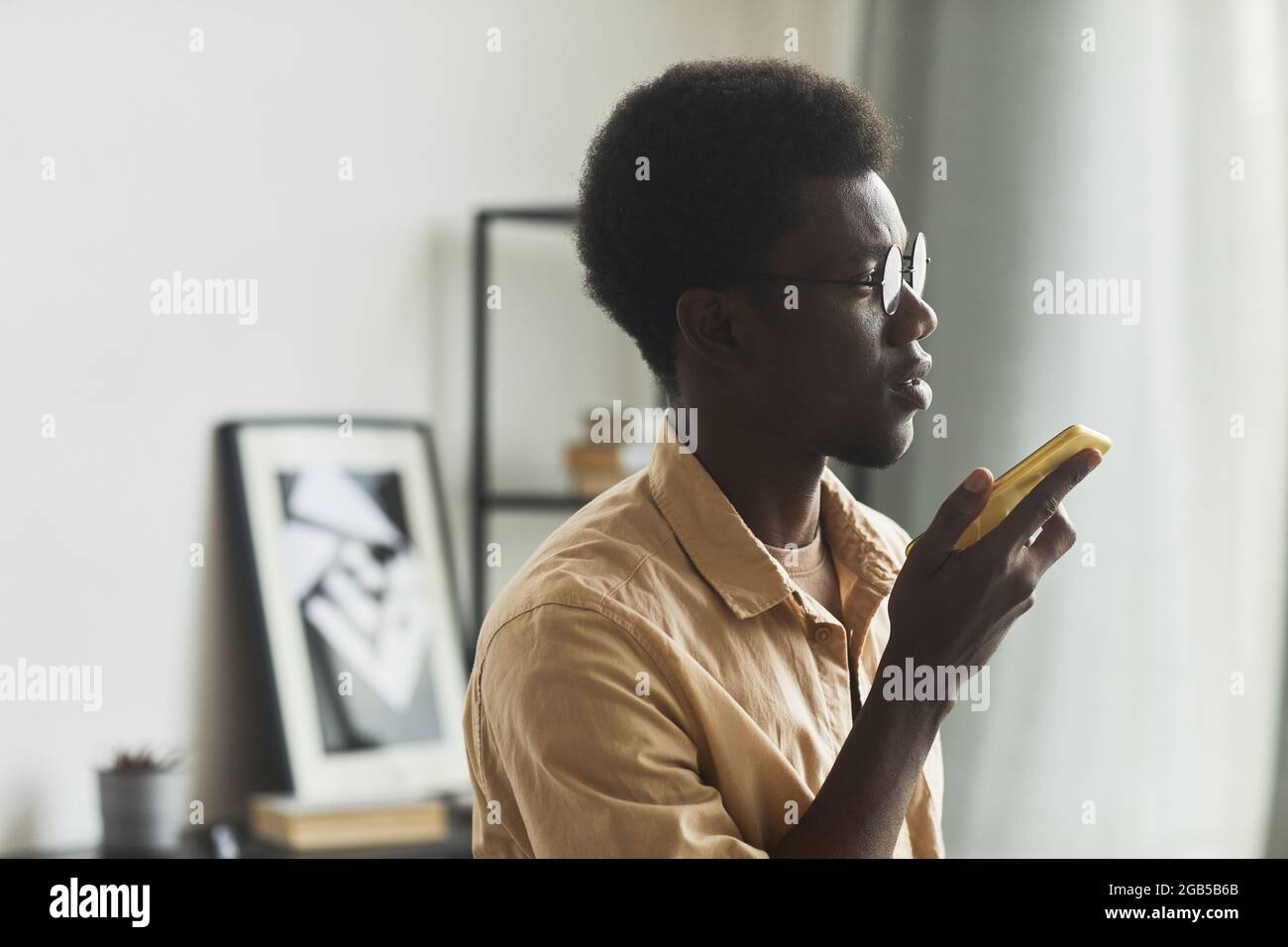 Primo piano di un giovane africano che usa il suo cellulare per una conversazione online in ufficio Foto Stock