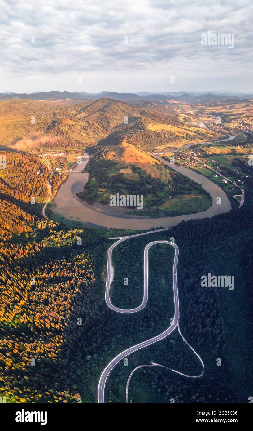 Antenna fuco vista sulle montagne di autunno con la strada di montagna serpentina, fiume e foresta. Fotografia di paesaggi Foto Stock