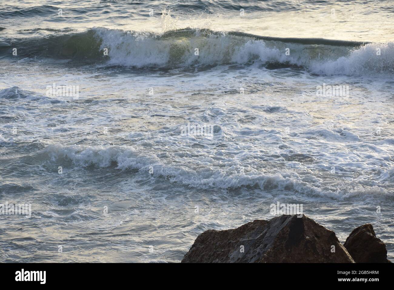 Onde rompere in acque gelide vicino Rocks a Shoreline Foto Stock