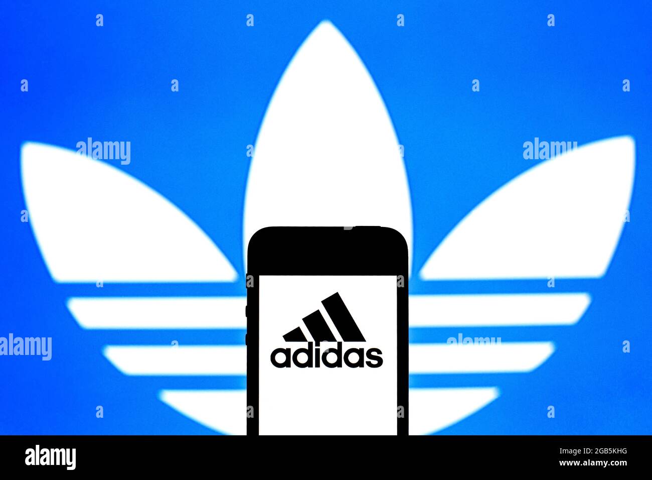 In questa illustrazione fotografica viene visualizzato un logo Adidas sullo  smartphone e sullo sfondo Foto stock - Alamy