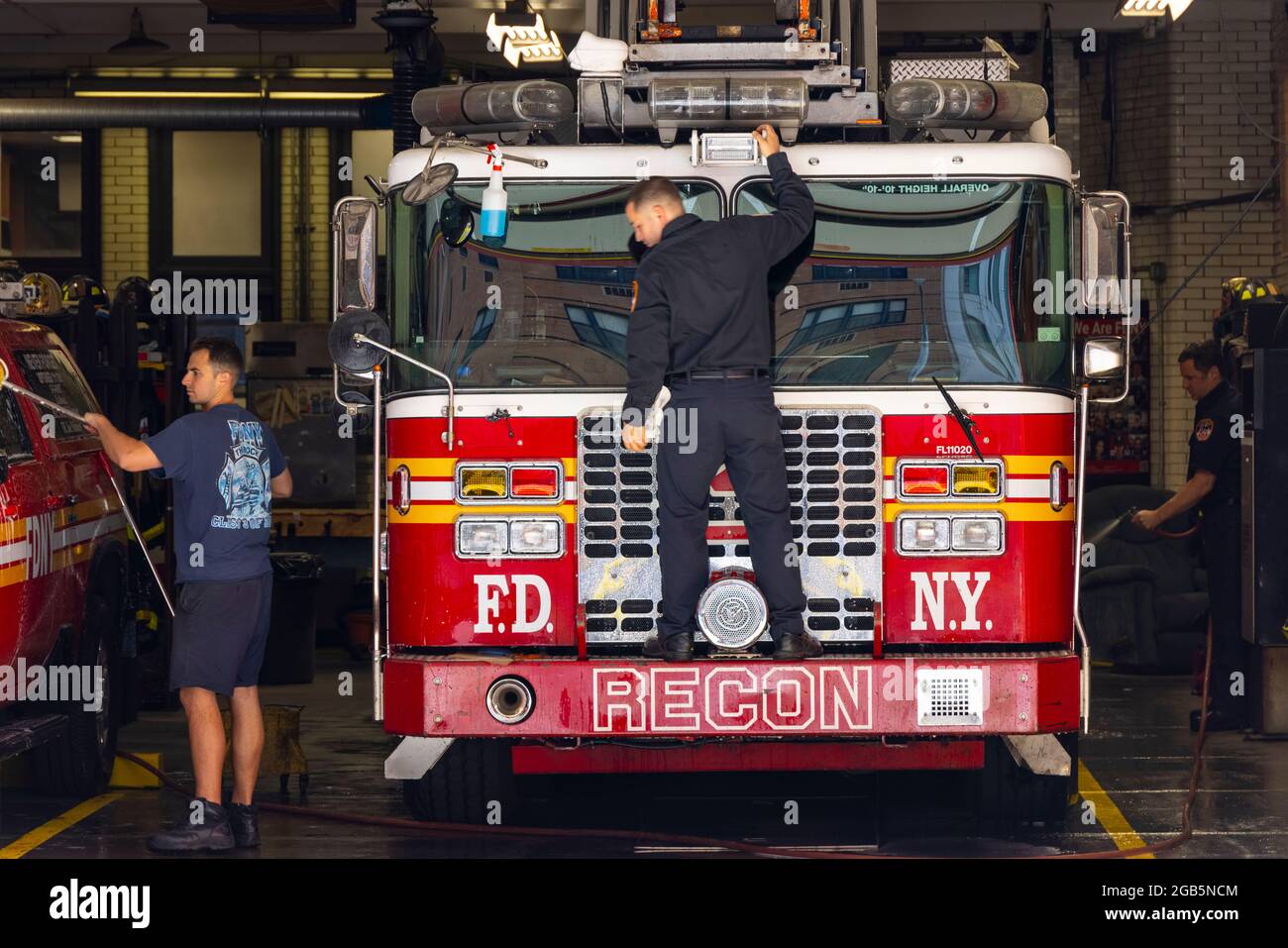 I vigili del fuoco lavano i camion dei vigili del fuoco al garage della scala 3 di FDNY NYC. Foto Stock