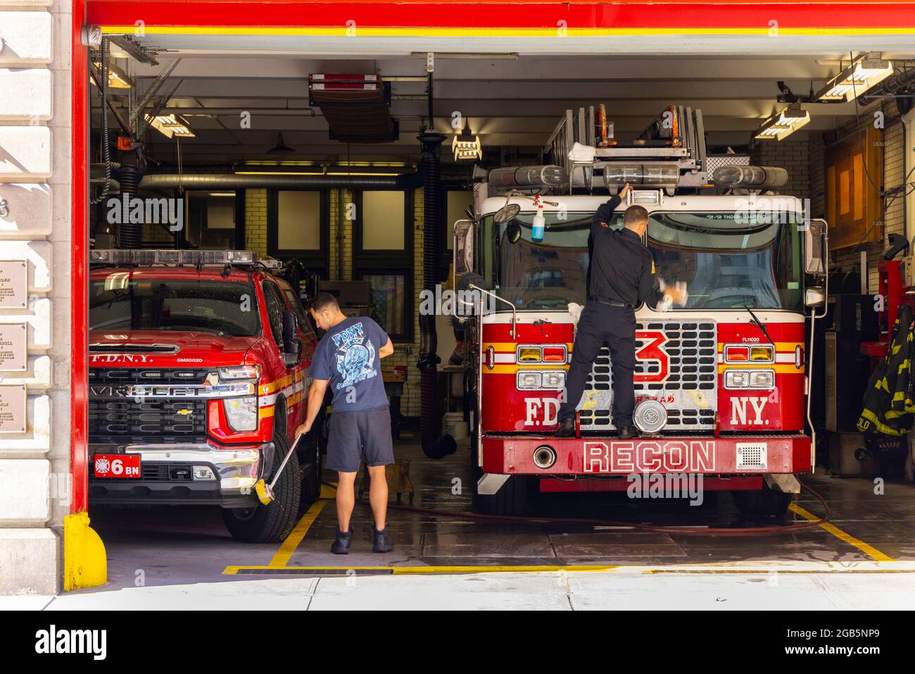 I vigili del fuoco lavano i camion dei vigili del fuoco al garage della scala 3 di FDNY NYC. Foto Stock