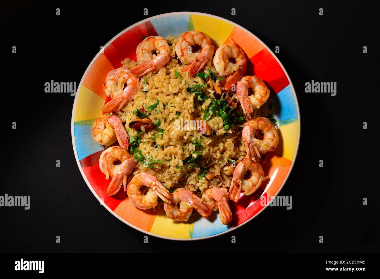 Piatto tradizionale italiano, risotto di pesce, riso con gamberi, cozze, aglio, vino bianco, prezzemolo su un piatto colorato e bello. Foto Stock