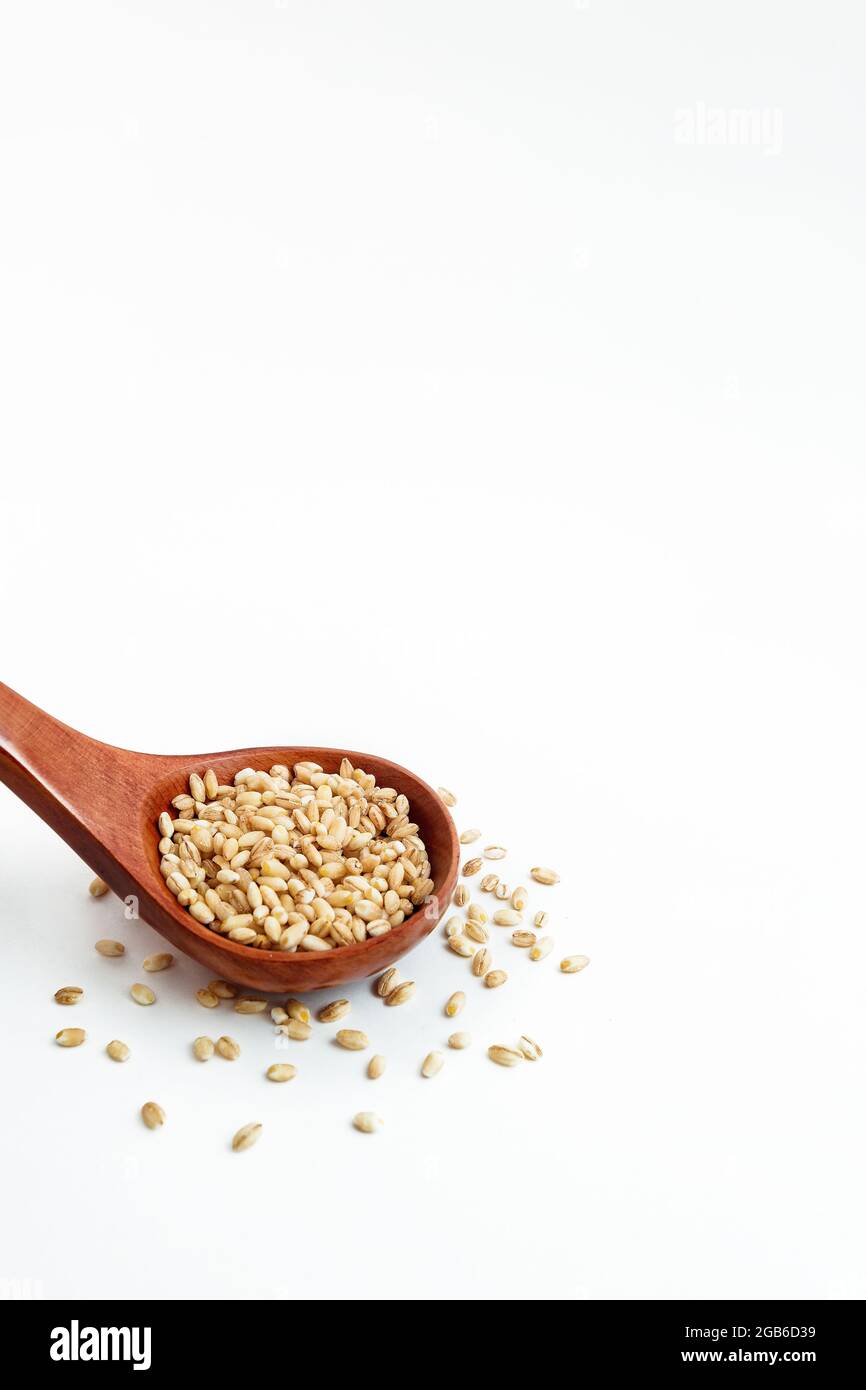 cucchiaio di legno con porridge d'orzo su fondo bianco Foto Stock