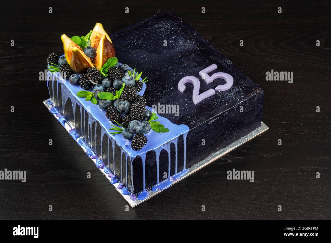 Bella deliziosa torta di compleanno su sfondo di legno scuro, con frutti di bosco e cioccolato fondente. Con numero venticinque. Foto Stock