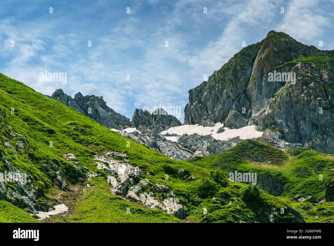 alpine Weiden an steilen Berghängen, mit Steinen und Blumen übersäht. Bergtal mit Wiesen und schroffen Felswänden. Klesenzaalpe, Grosswalsertal Foto Stock