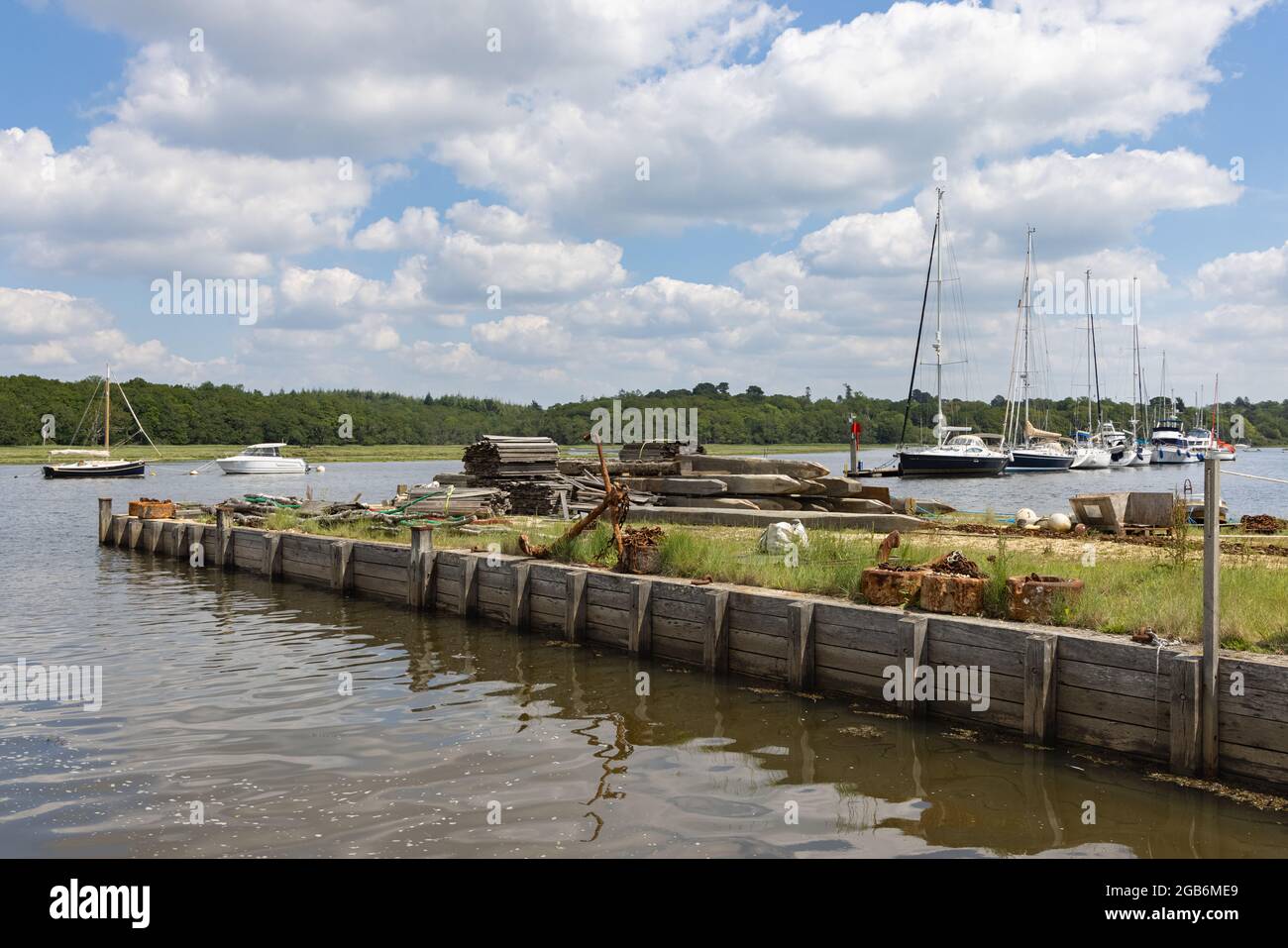 Buckler's Hard, Hampshire, Regno Unito, 23 giugno 2021: Un'ancora arrugginita e catene su un molo di legno nel fiume Beaulieu su cui sono ormeggiati gli yacht. Foto Stock