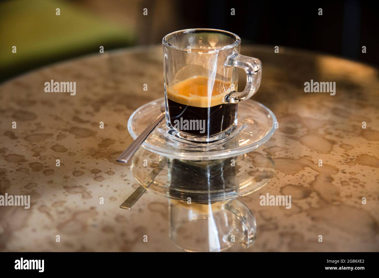 Primo piano ritratto di un'elegante tazza di caffè espresso seduta su un elegante tavolo a specchio colorato con riflessi. Foto Stock