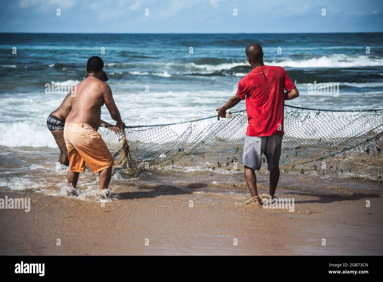 Salvador, Bahia, Brasile - 23 maggio 2021: Pescatori che tirano la rete da pesca dal mare con pesce all'interno. Spiaggia di Boca do Rio a Salvador. Foto Stock