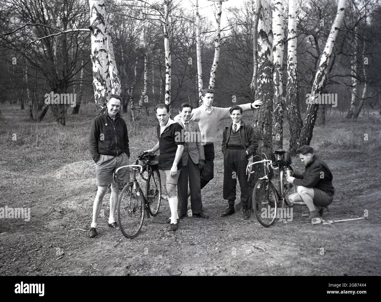1954, membri storici e maschili di un club ciclistico in piedi per una foto in una zona boscosa illuminata di Epping Forest, Loughton, Essex, Inghilterra, Regno Unito. Foto Stock
