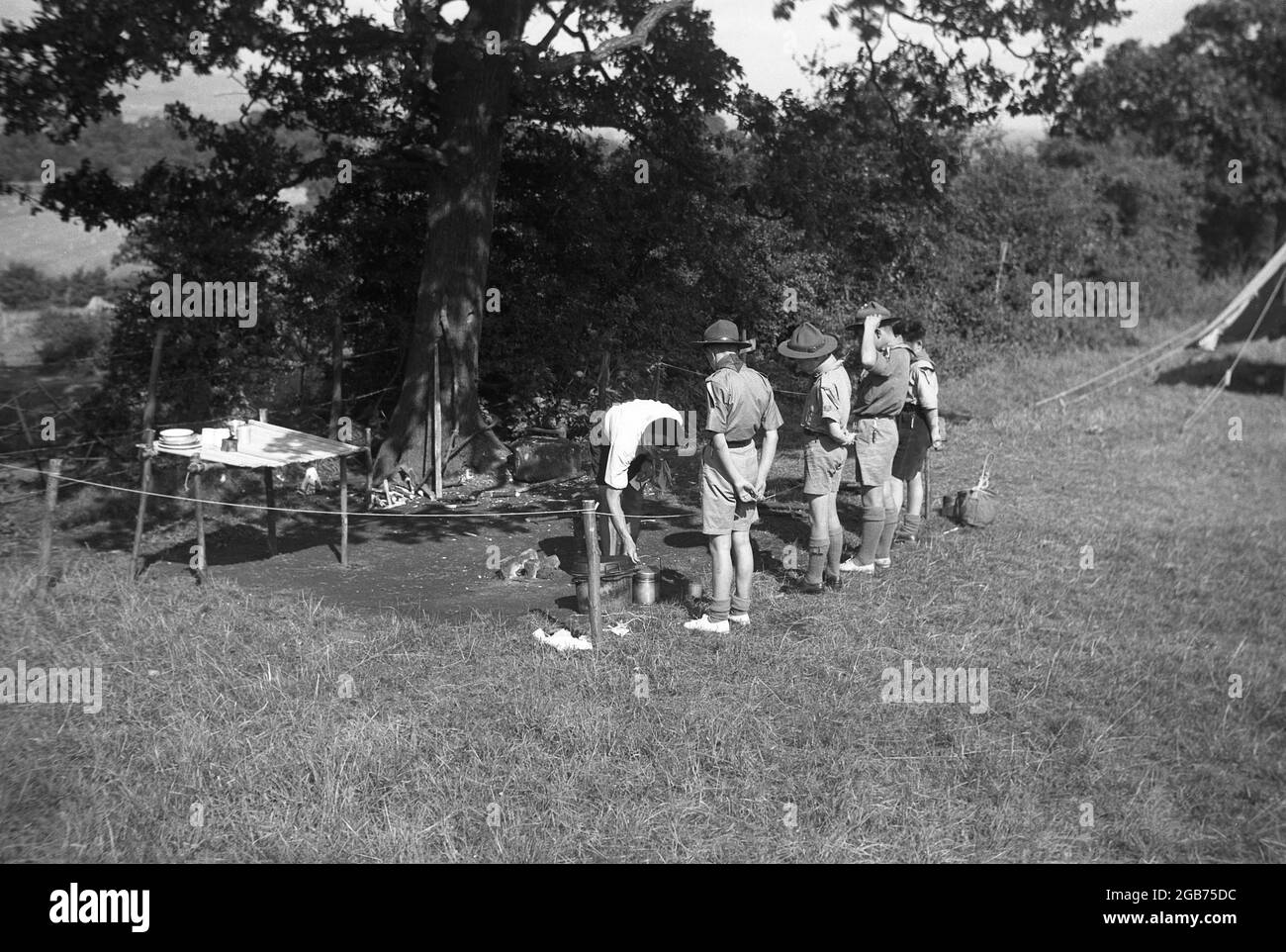 1951, storico, un'ispezione da parte di un maestro scout dei preparativi per l'area di cottura del campo scout, segnato al bordo del campeggio, Inghilterra, Regno Unito. Foto Stock