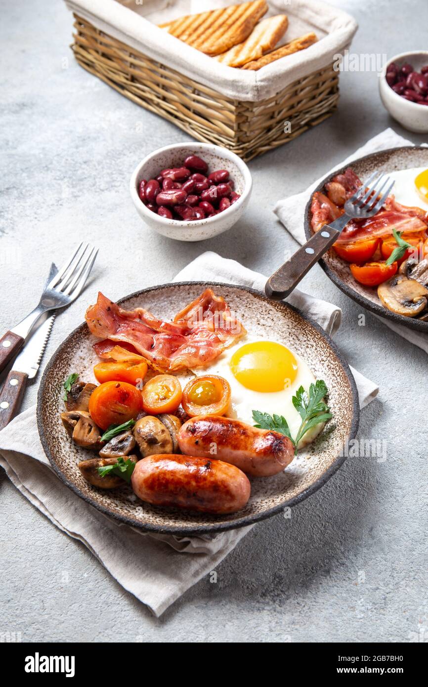 Colazione inglese con uova fritte, pancetta, salsicce, fagioli, toast su sfondo bianco Foto Stock