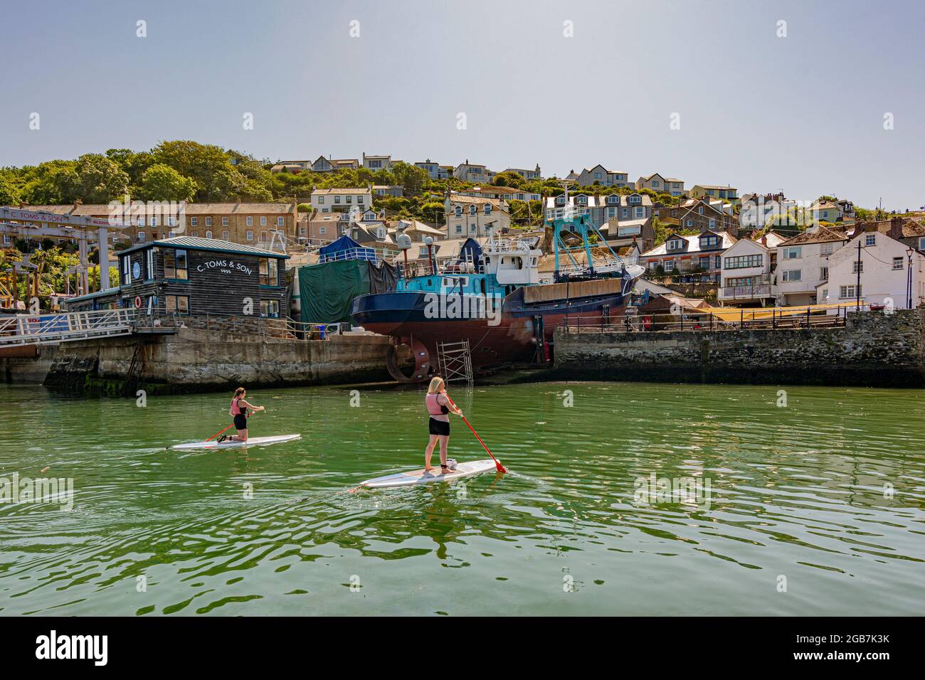 Due Paddleboarders che arrivano a Polruan Quayside in Cornovaglia, Regno Unito. Foto Stock