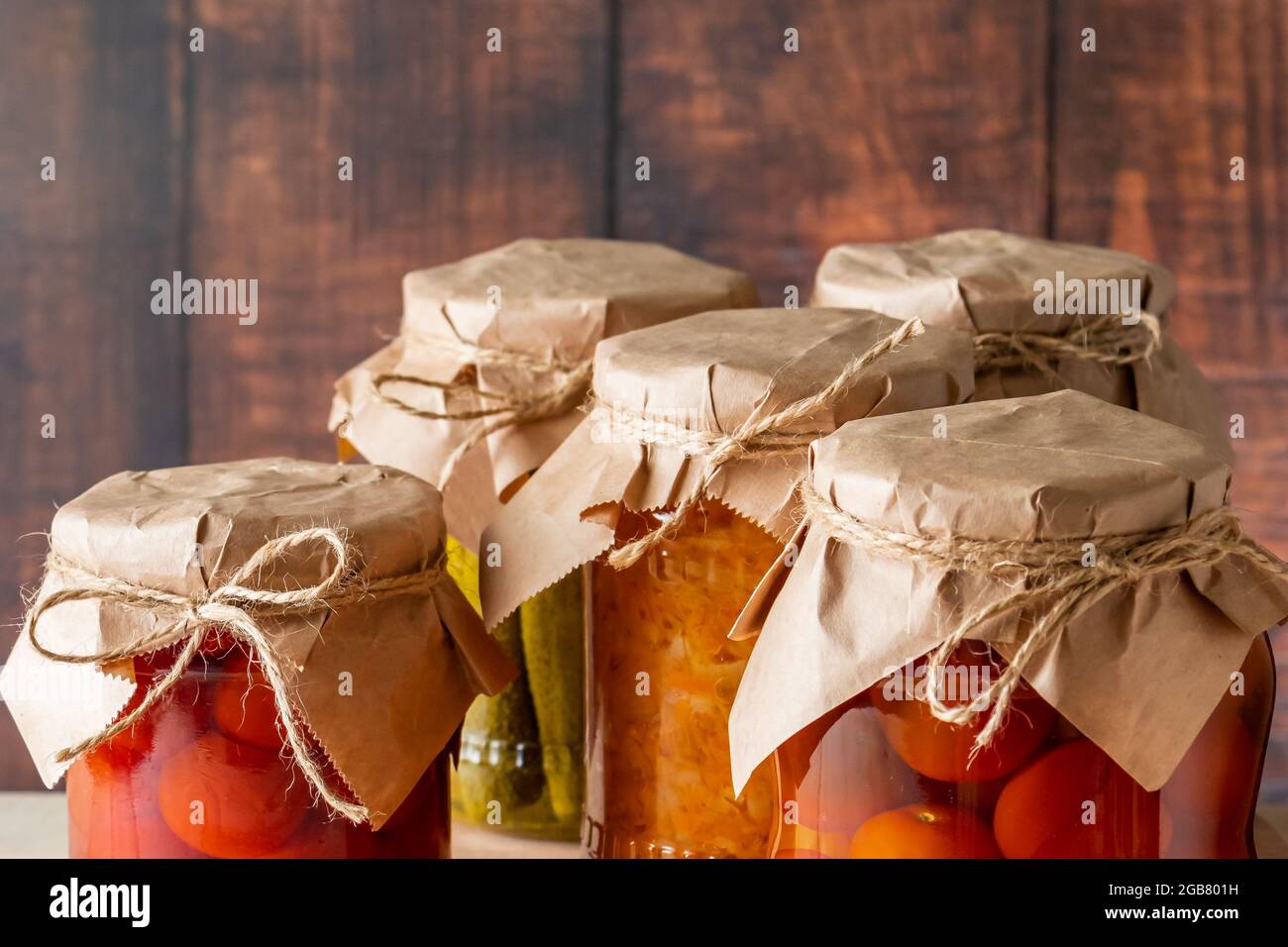 Vasetti di verdure fermentate su sfondo ligneo. Cetrioli in scatola fatti in casa, pomodori e crauti. Foto Stock