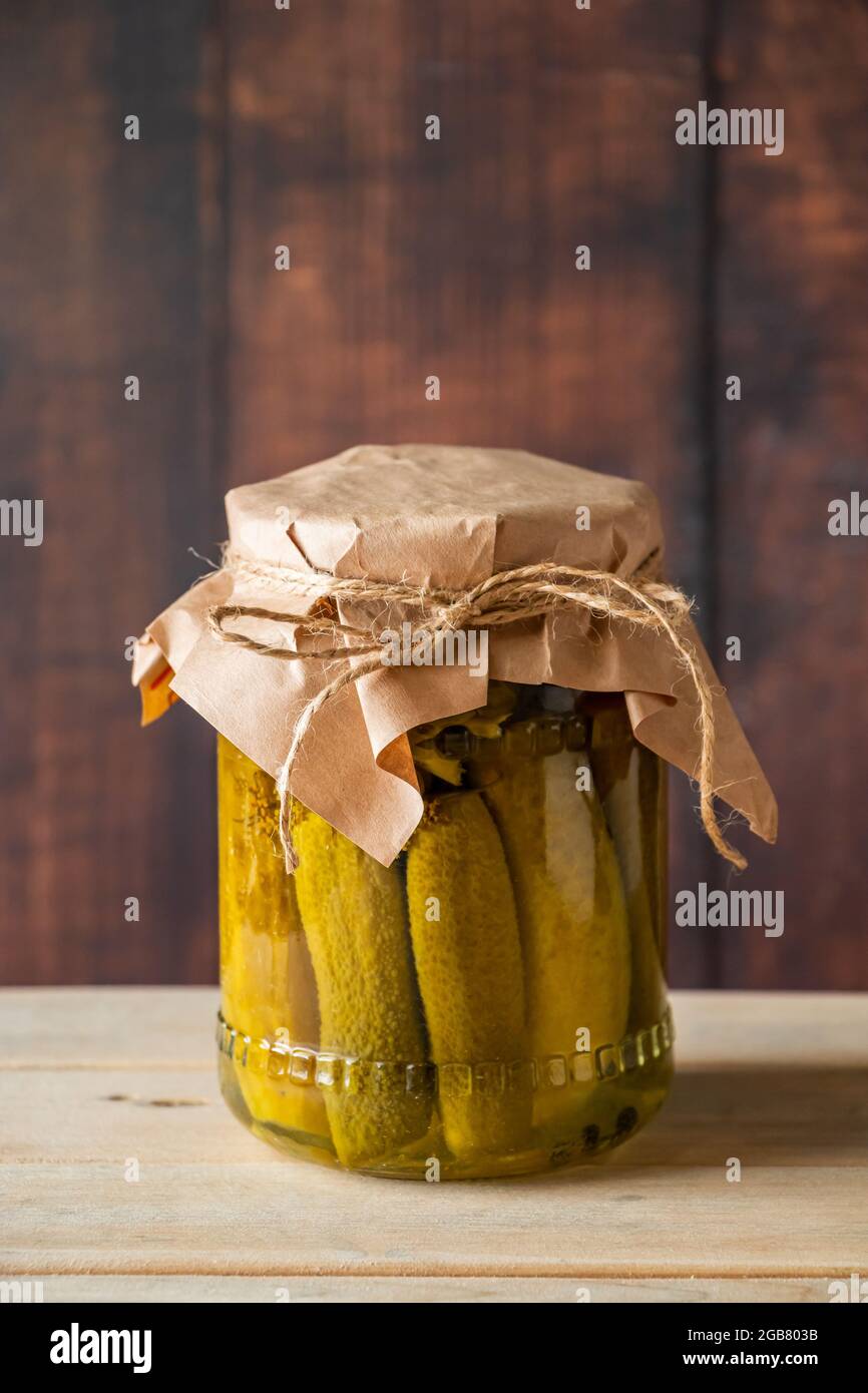 Cetrioli decapati in un vaso di vetro su sfondo di legno. Cibo fermentato di tendenza. Stile rustico in casa. Foto Stock