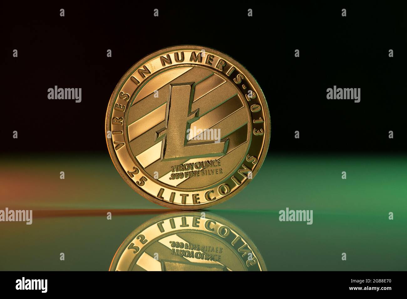 Moneta fisica a criptovaluta LTecoin LTC posizionata su una superficie riflettente e illuminata da luci verdi e rosse Foto Stock