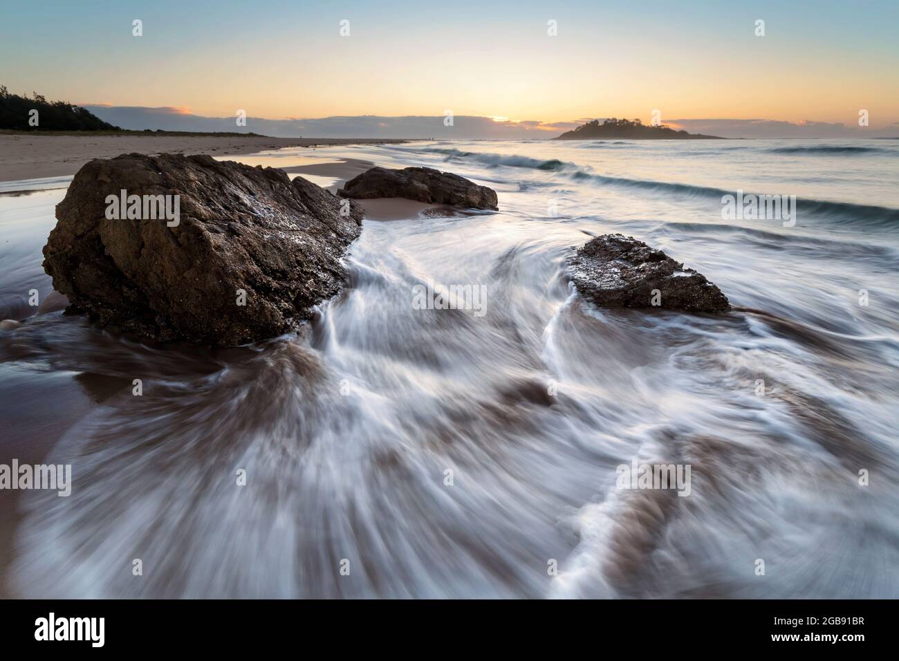 acqua intorno alle rocce su una spiaggia vicino all'oceano Foto Stock