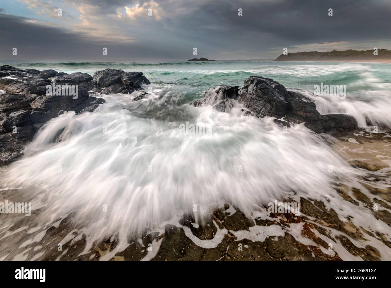 acqua che si riversa attraverso le rocce sulla spiaggia Foto Stock