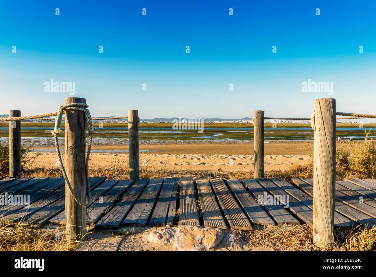 Passerelle in legno con vista sulle zone umide di Ria Formosa sulla penisola di Faro Beach, Faro, Algarve, Portogallo Foto Stock