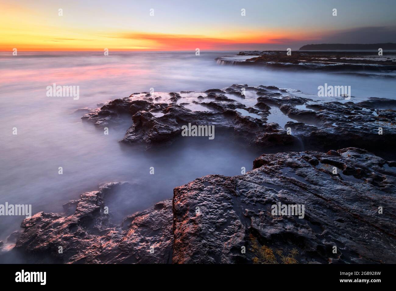 alba sopra le rocce sulla costa Foto Stock