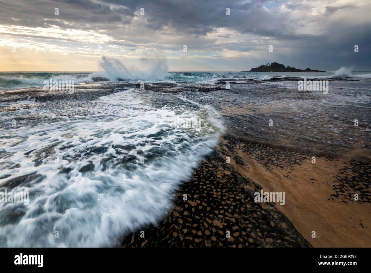 onde che sprigionano sulle rocce della spiaggia Foto Stock