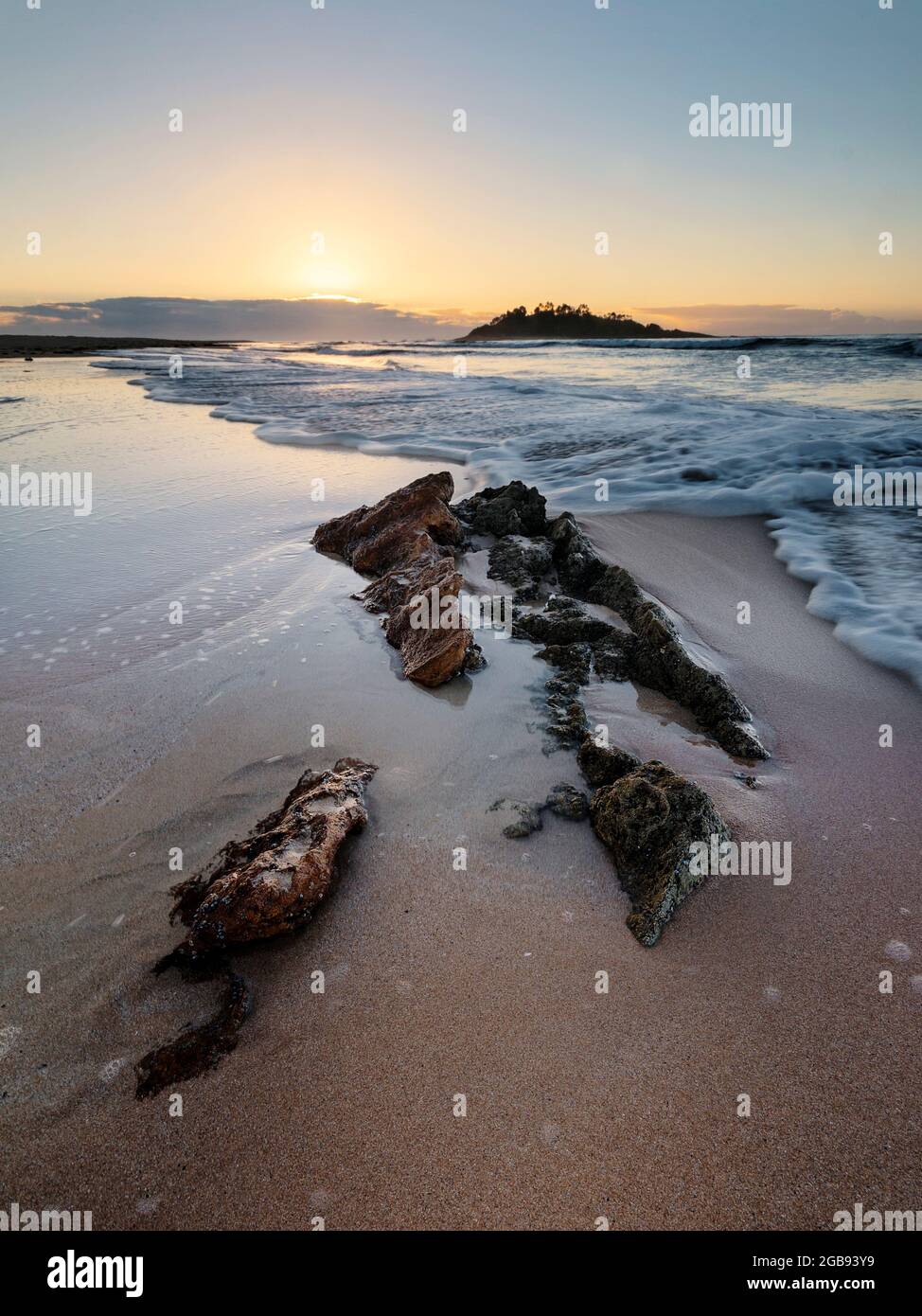 onde su una spiaggia rocciosa all'alba Foto Stock