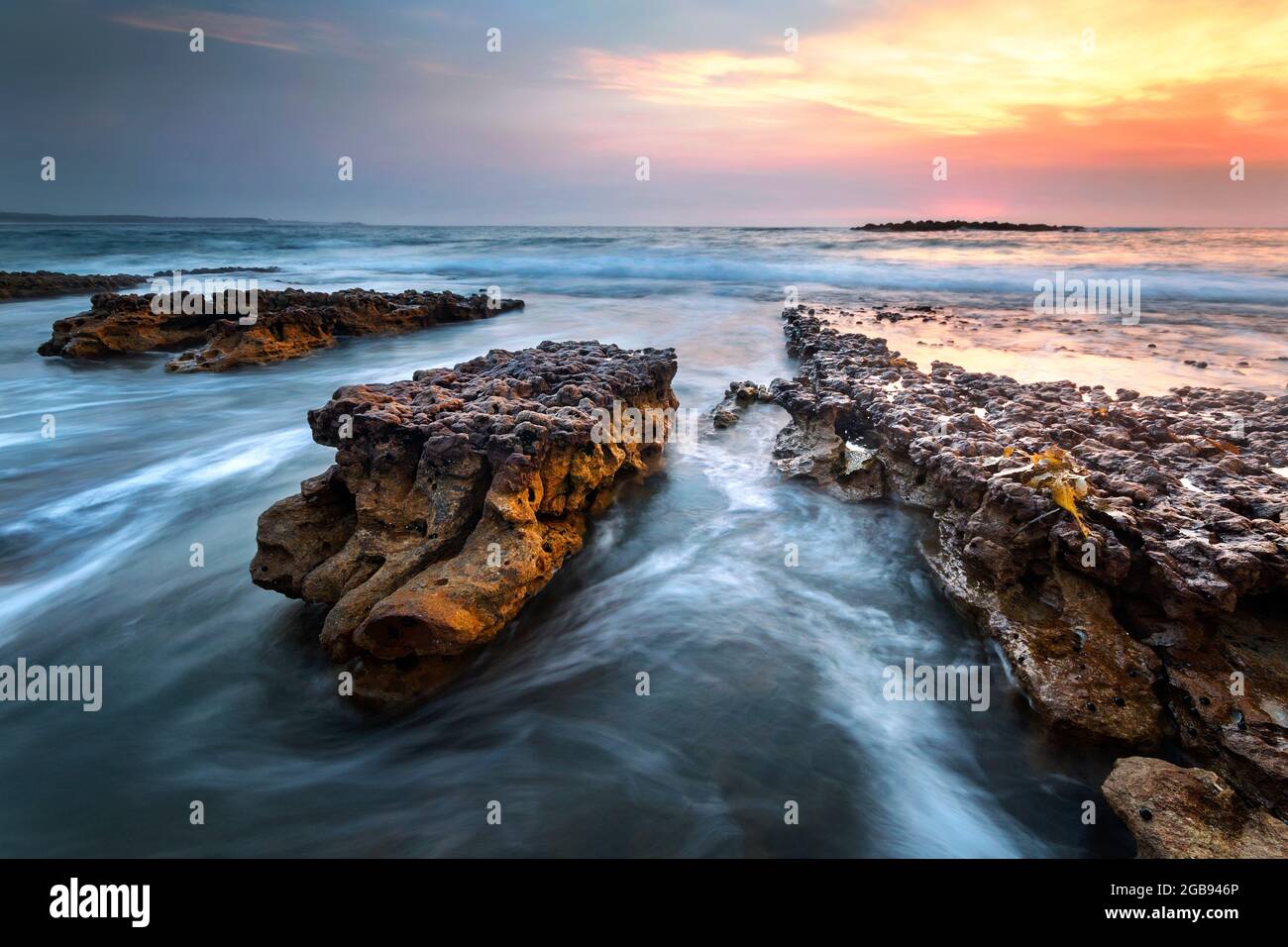 acqua e rocce all'alba sulla costa Foto Stock