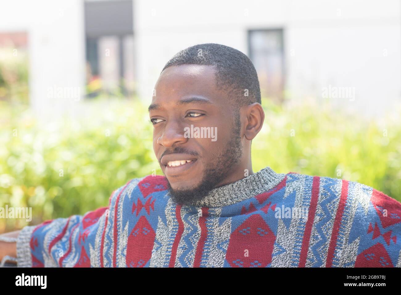 Giovane uomo nero seduto in panchina con poncho africano, Friburgo, Baden-Wuerttemberg, Germania Foto Stock