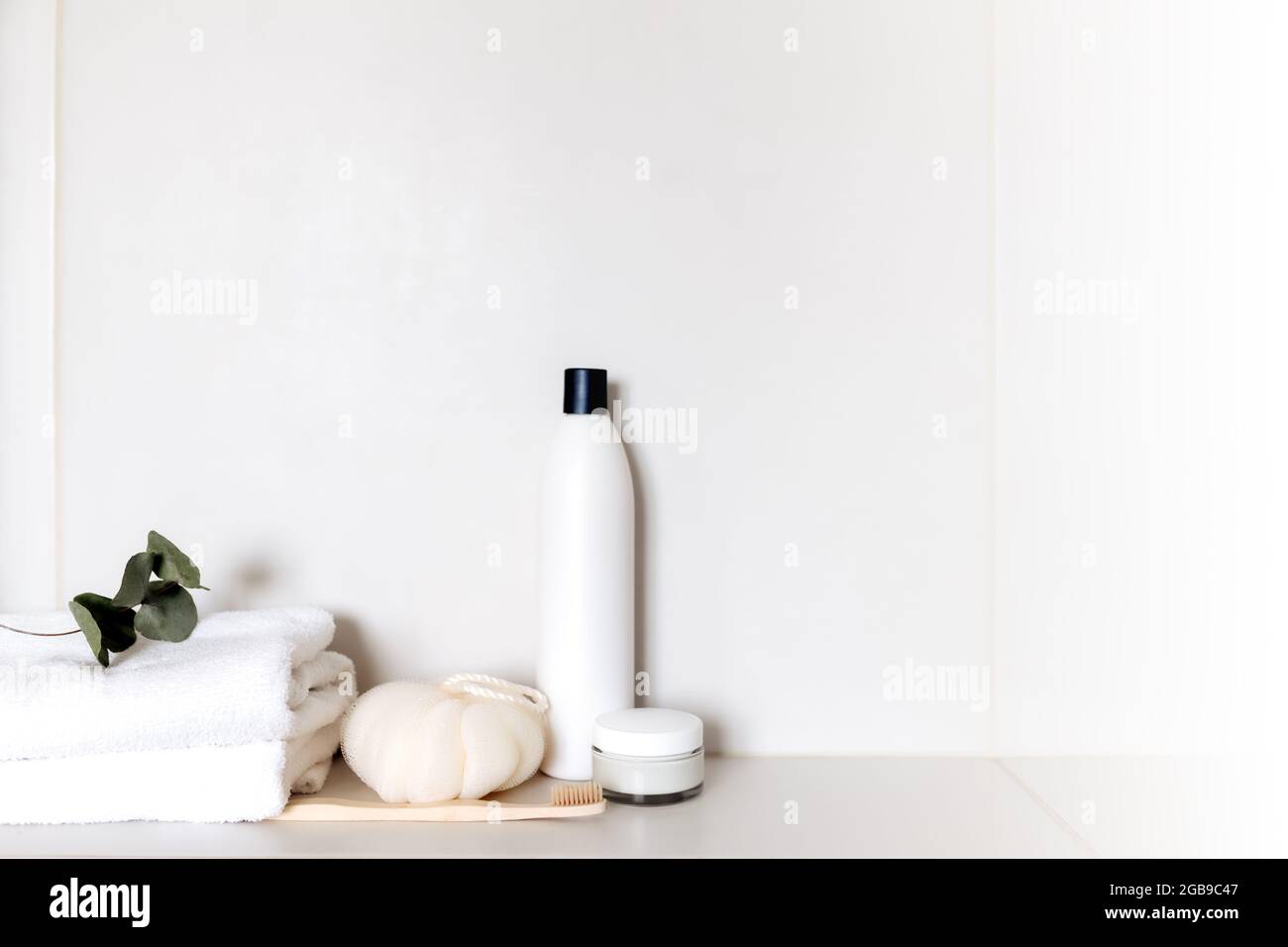 Ripiano per bagno bianco con diversi accessori da bagno. Concetto di pulizia dell'hotel. Concetto domestico. Panno, shampoo, crema, pianta, spazzolino da denti, spazzola, Foto Stock