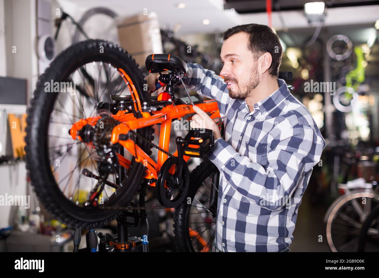 il maschio premuroso monta le parti della bicicletta per il montaggio in negozio Foto Stock