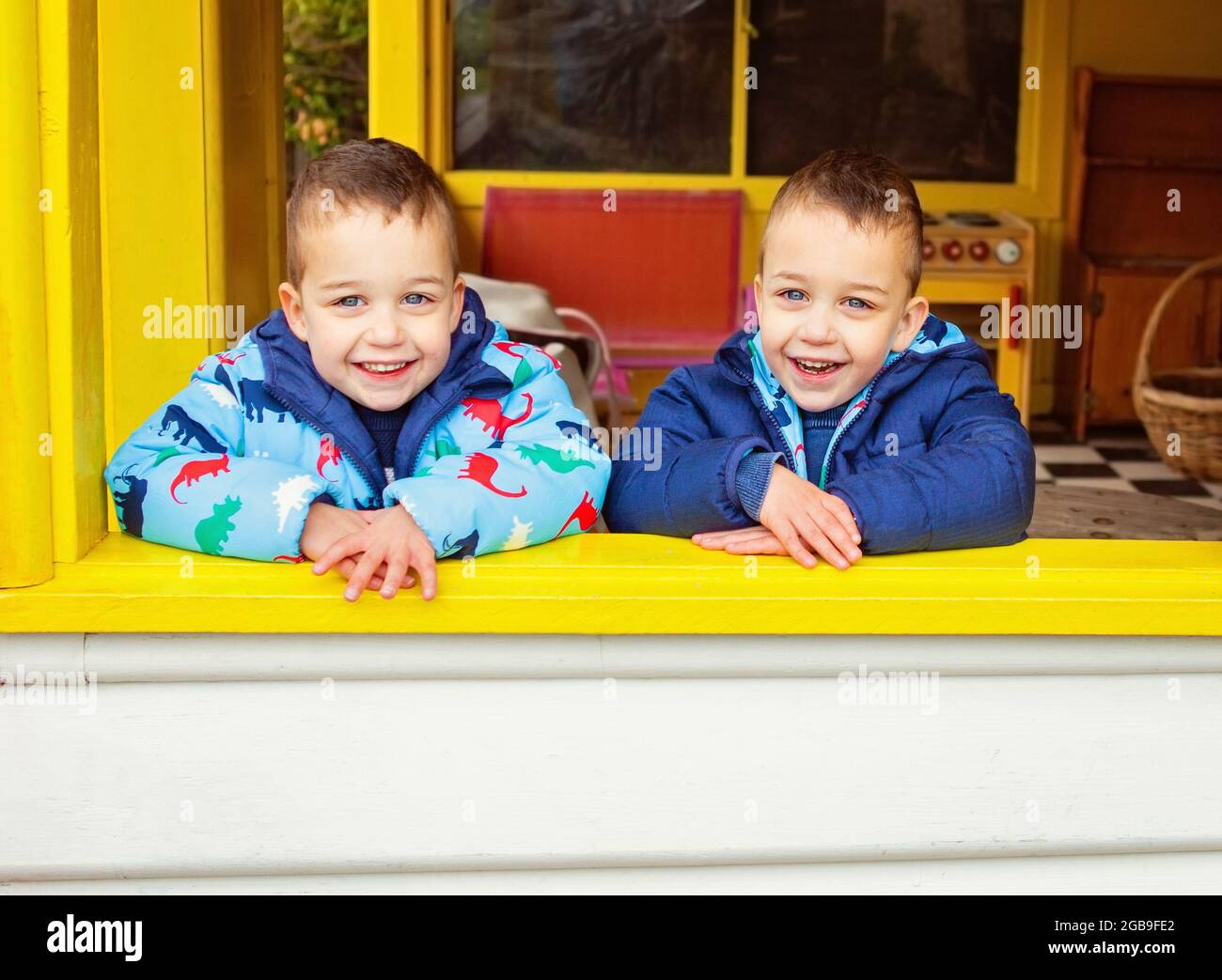 fratelli gemelli appoggiati su una finestra sorridente Foto Stock