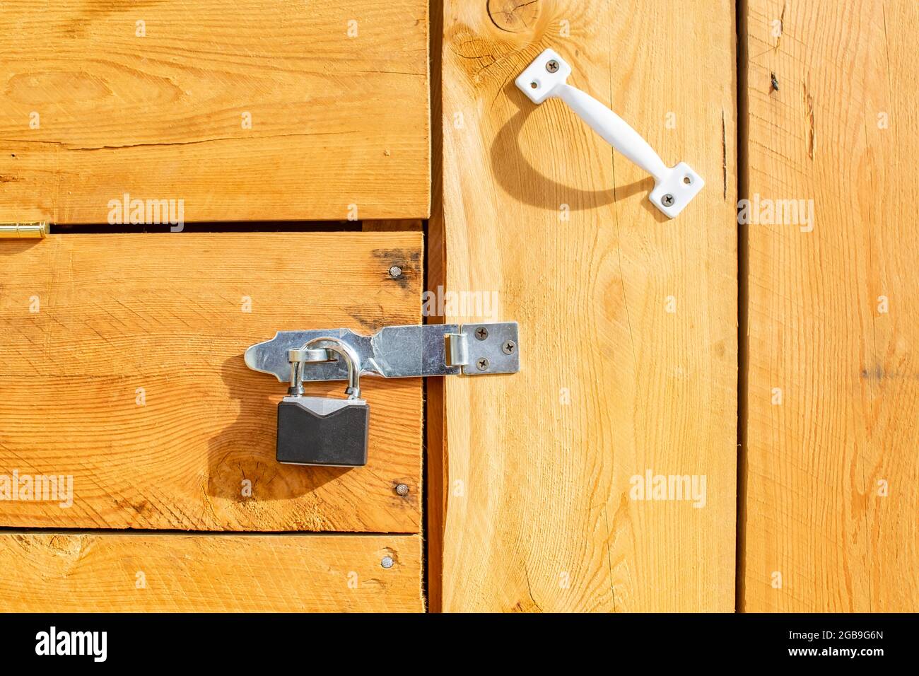 un lucchetto di metallo è appeso alla porta di legno della casa Foto Stock