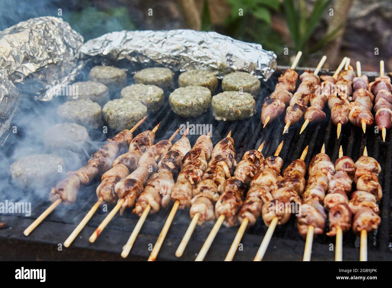 Hamburger al barbecue, cuori grigliati su spiedini e barbecue di fumo festa. Primo piano. Foto Stock