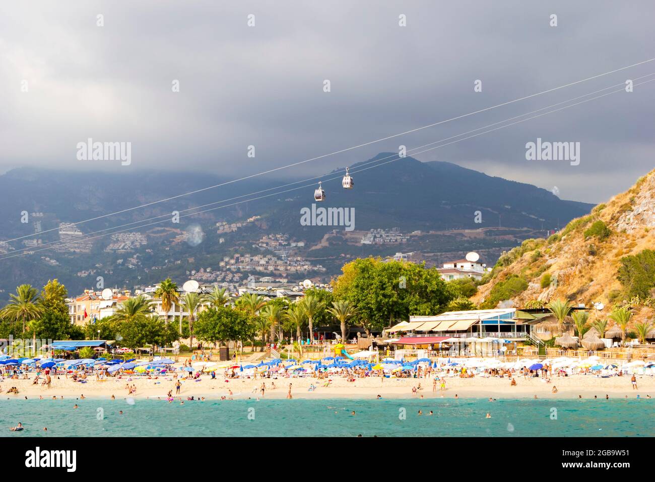 Turchia, Alanya, Cleopatra spiaggia - 30 agosto 2017: Persone sulla spiaggia, vista dal mare, sullo sfondo di montagne e funicolare. Foto Stock