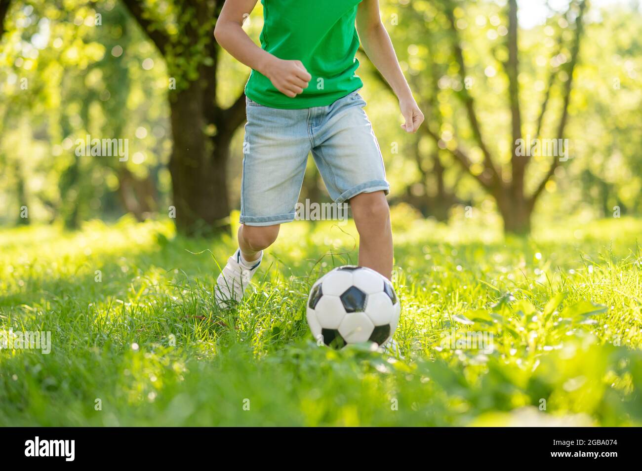 Bambino junior che gioca a calcio sul prato verde Foto Stock