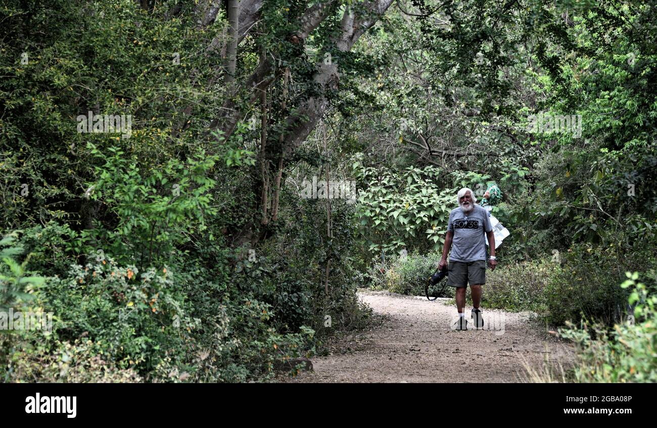 Un uomo anziano con una macchina fotografica sta camminando lungo un percorso nel World Butterfly Sanctuary, a Mission, nel Texas del sud. Foto Stock