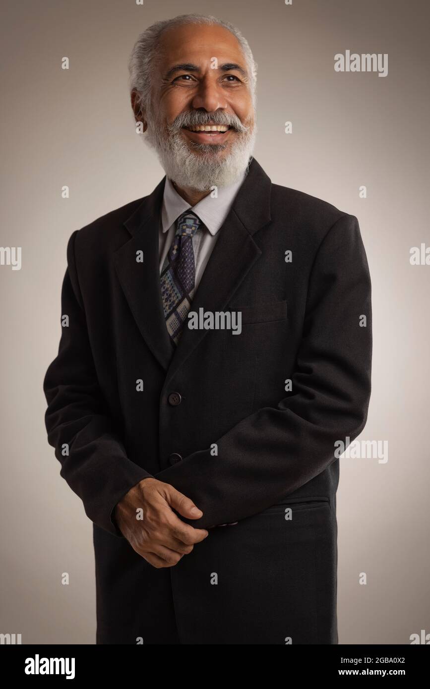UN VECCHIO IN ABBIGLIAMENTO FORMALE FELICEMENTE IN PIEDI E SORRIDENTE Foto Stock